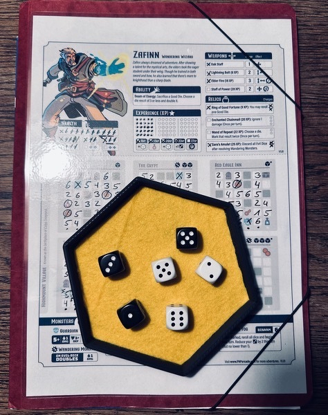A detailed look at a character sheet from a print and play role-playing game, Zaffinn. Featuring stats, abilities, etc. On top a dice tray with six dice - three white, three black.